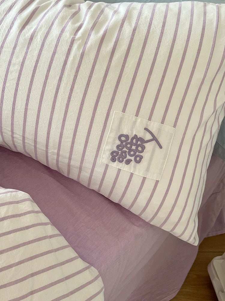 Close-up of a purple striped pillowcase with a stitched grape applique patch.