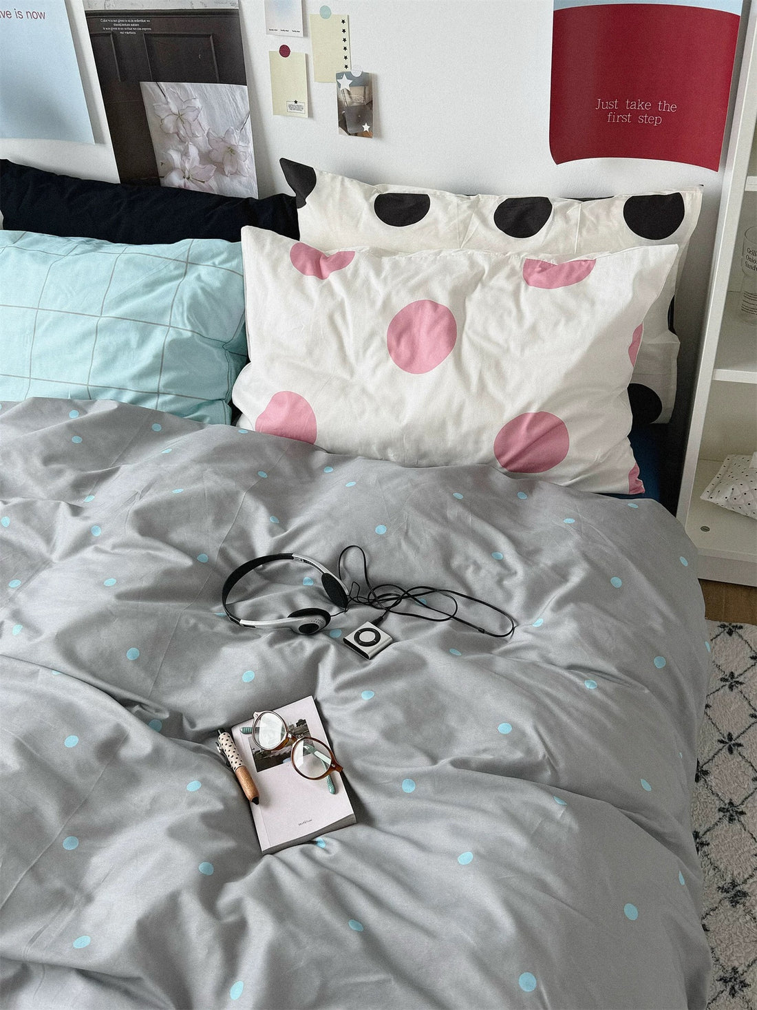 Gray blue polka dot bedding set with a blue sheet and layered check and dot pillows.