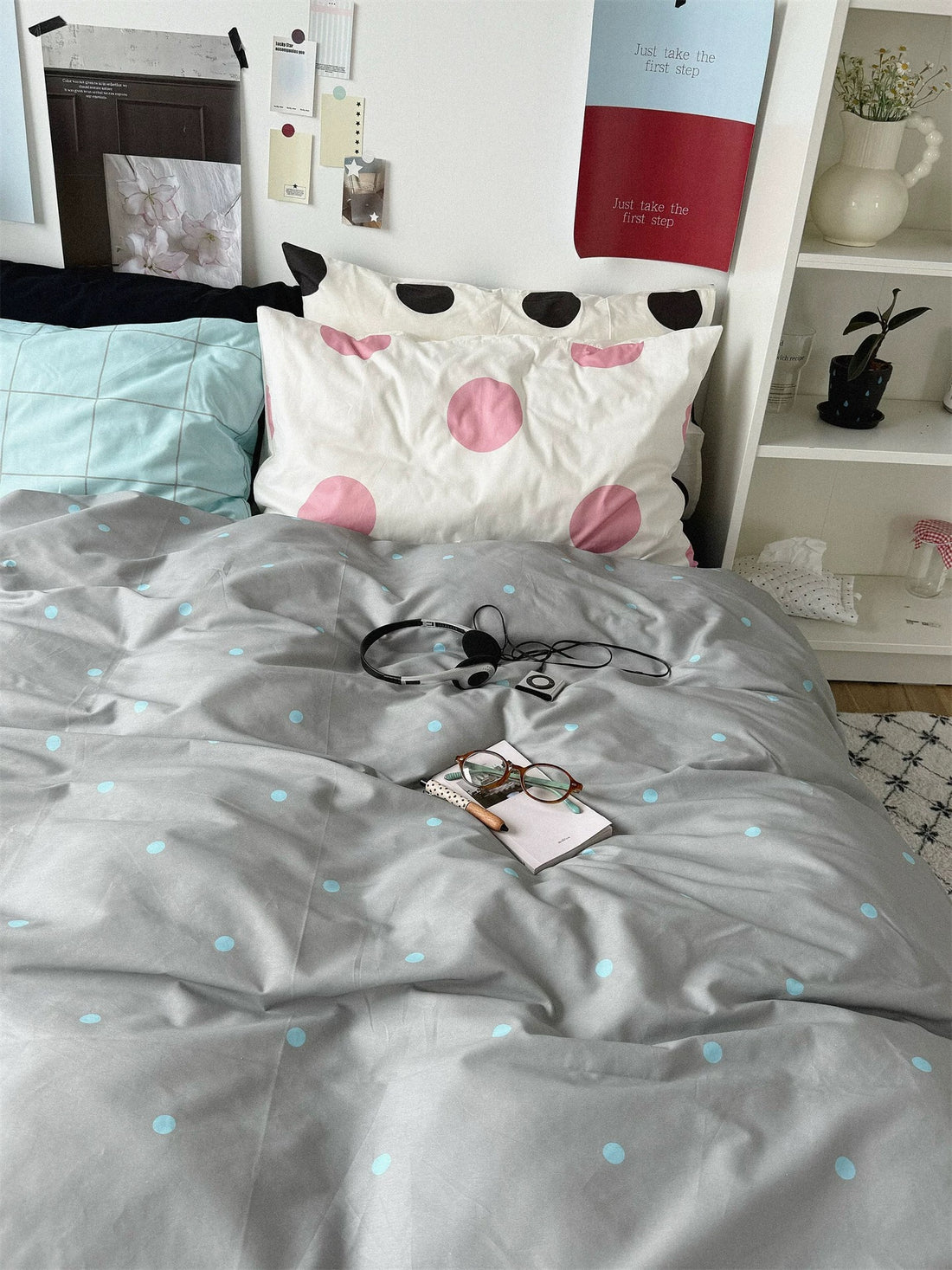 Gray blue polka dot bedding set with a blue sheet and layered check and dot pillows.