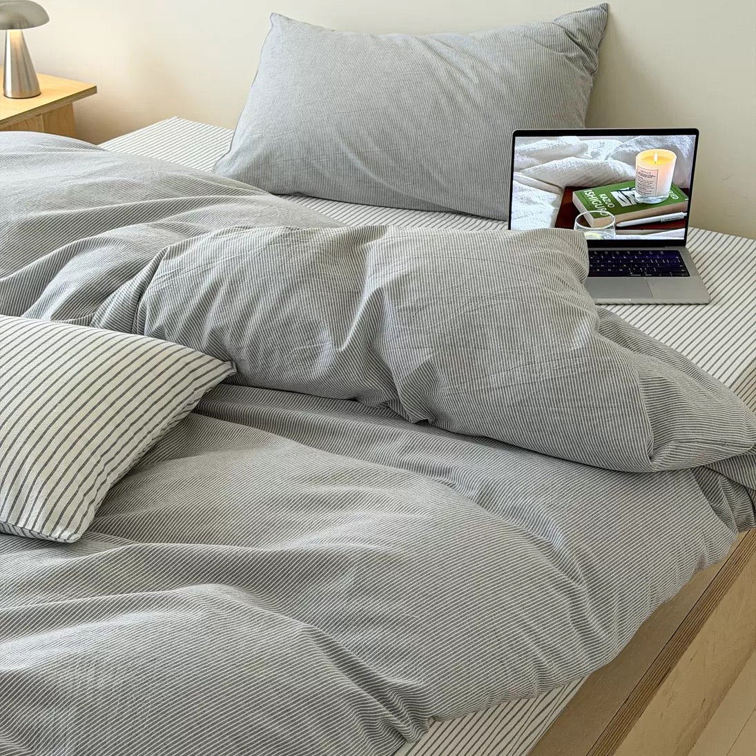Neutral gray striped duvet cover layered across platform bed with matching cotton pillowcases and flat sheet perfectly.