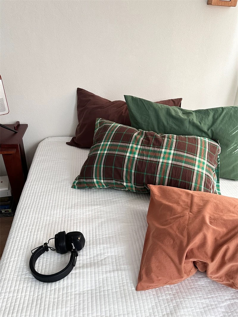 Brown and green plaid pillowcases sit among plain green, rust orange and cocoa brown designs.