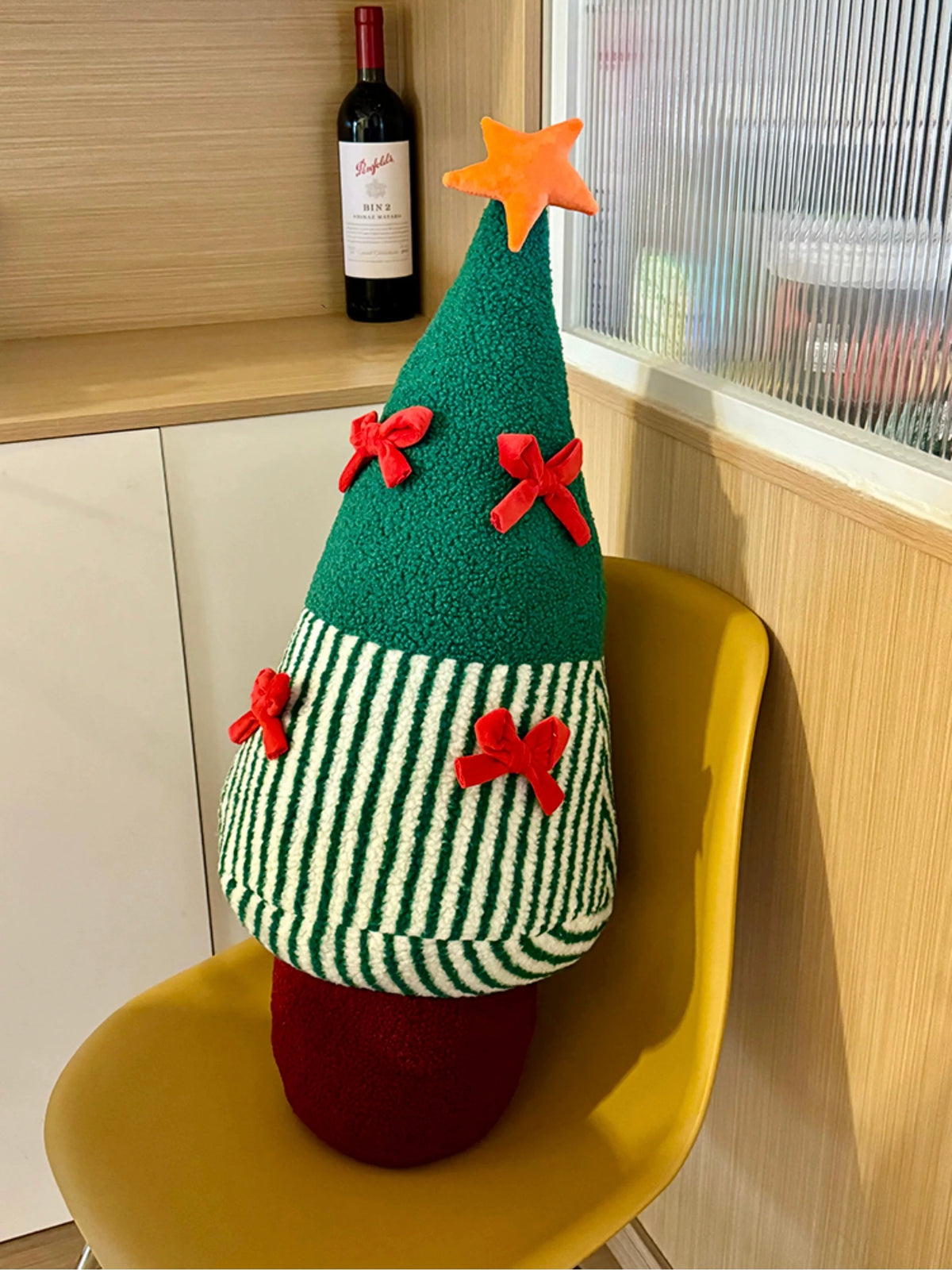 Green Christmas tree pillow with red bows styled on a chair