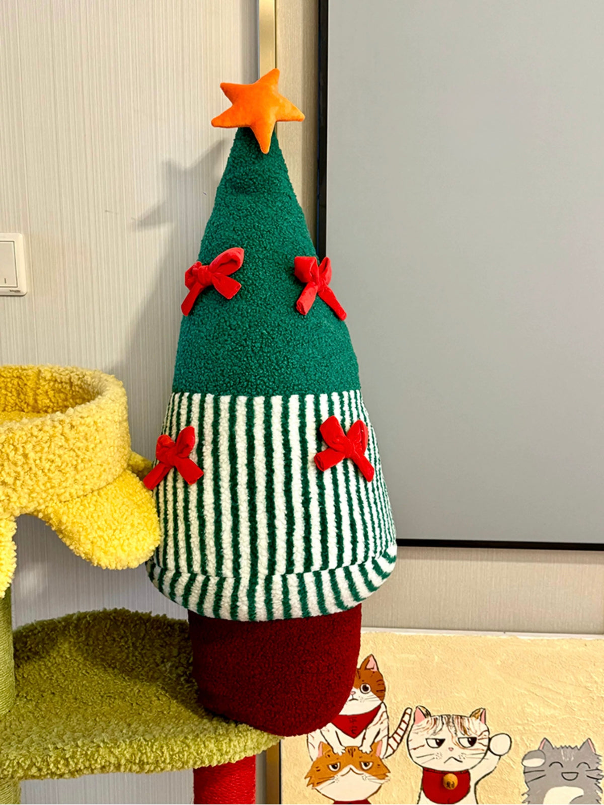 Green Christmas tree shaped pillow with striped lower section in a holiday room