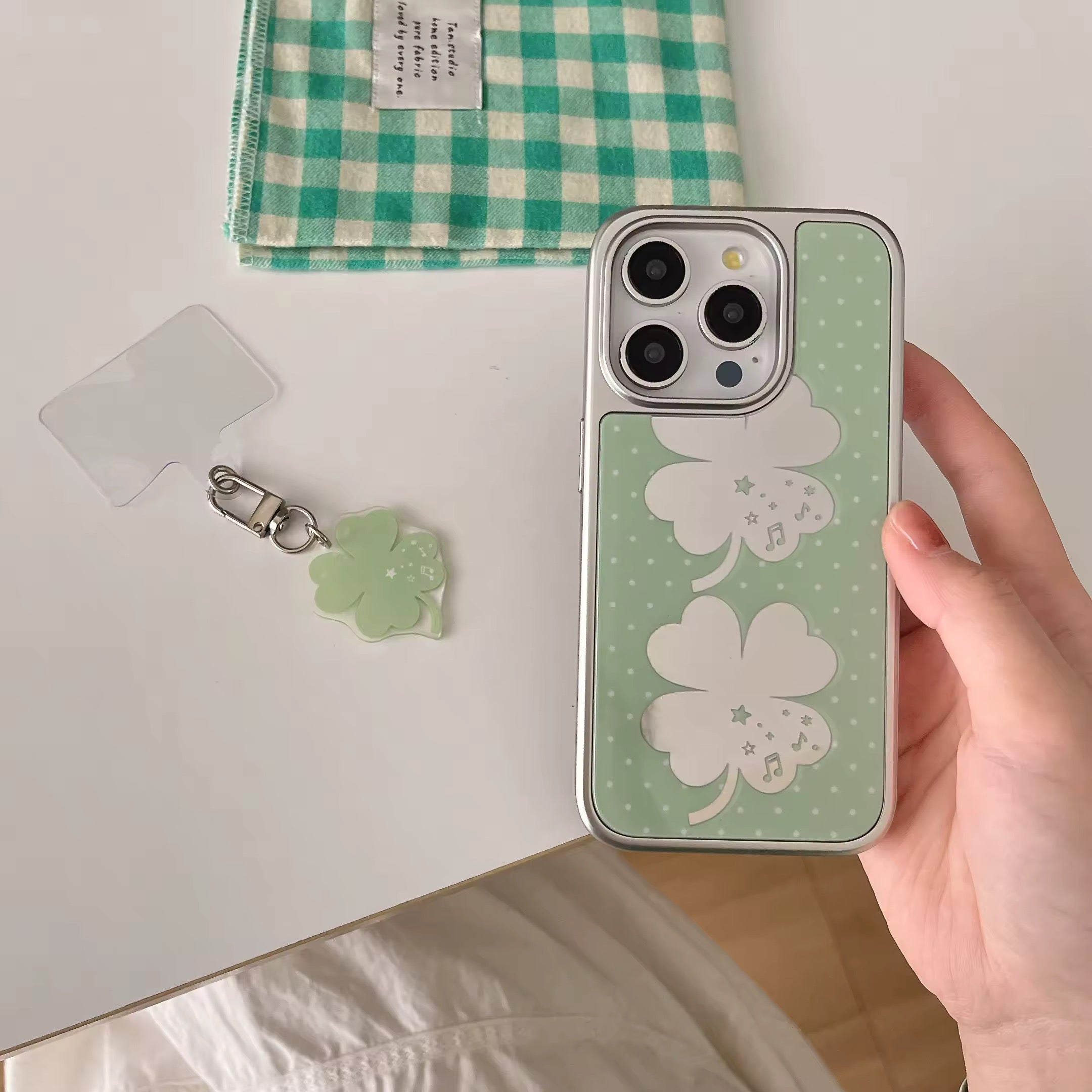 Green clover iPhone case with mirror finish and white polka dots shown on hand