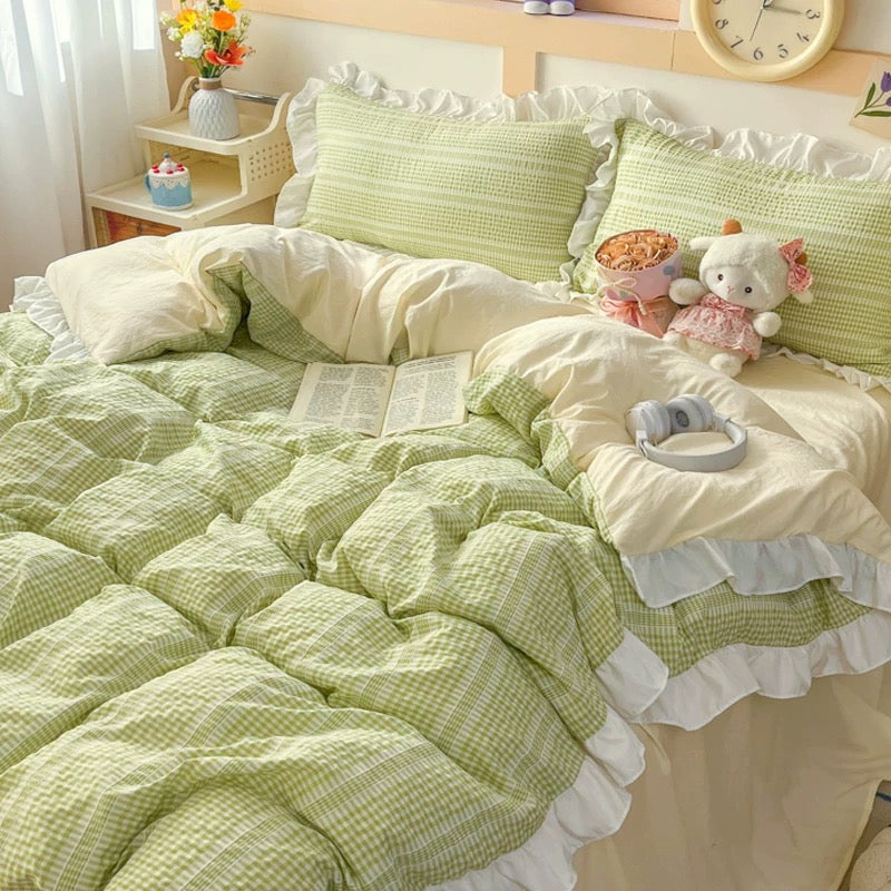 Bed with green and white checkered bedding, pillows, and a teddy bear.