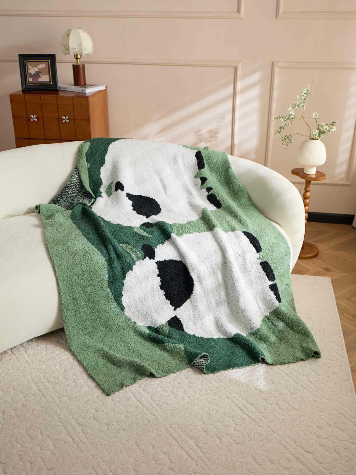 Green throw blanket with two large white sheep, black faces, black feet, and fuzzy texture.
