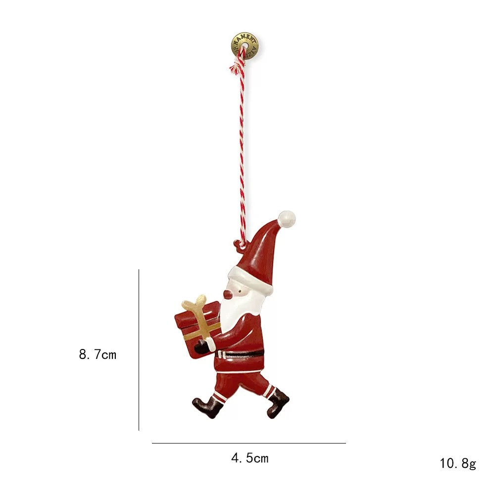 Hand painted Christmas ornaments include this red Santa holding a gift box with a gold ribbon.