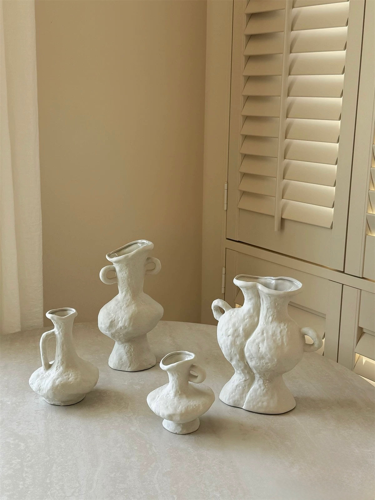 Set of white textured vases on a light surface with a neutral background
