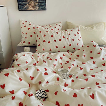 Red heart bedding set on a white bed with matching heart pillowcases and bedside decor