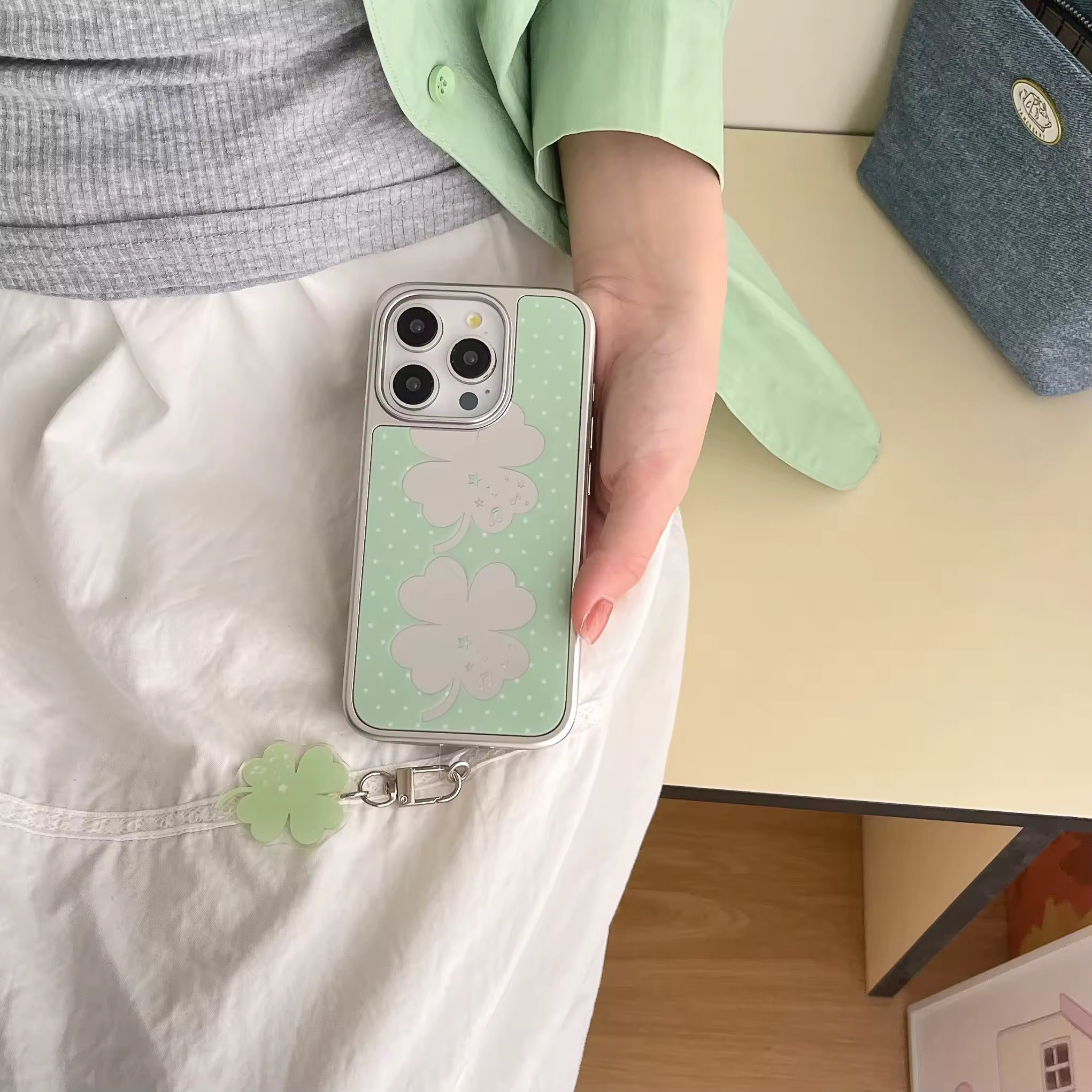 Green iPhone case with charm and cute desk setup with coffee and books