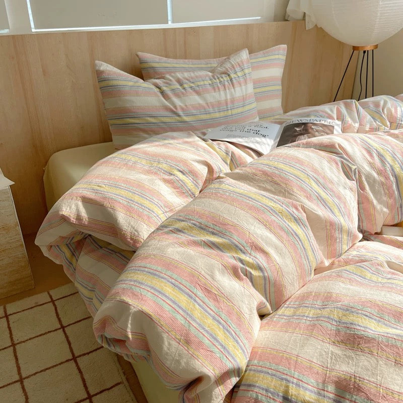 Bed with striped bedding and pillows in a room with wooden walls and a tiled floor.