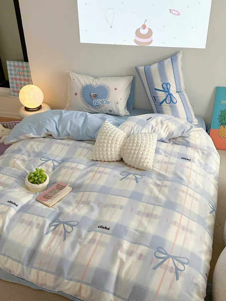 Bed with blue and white checkered duvet and decorative pillows in a bedroom setting.