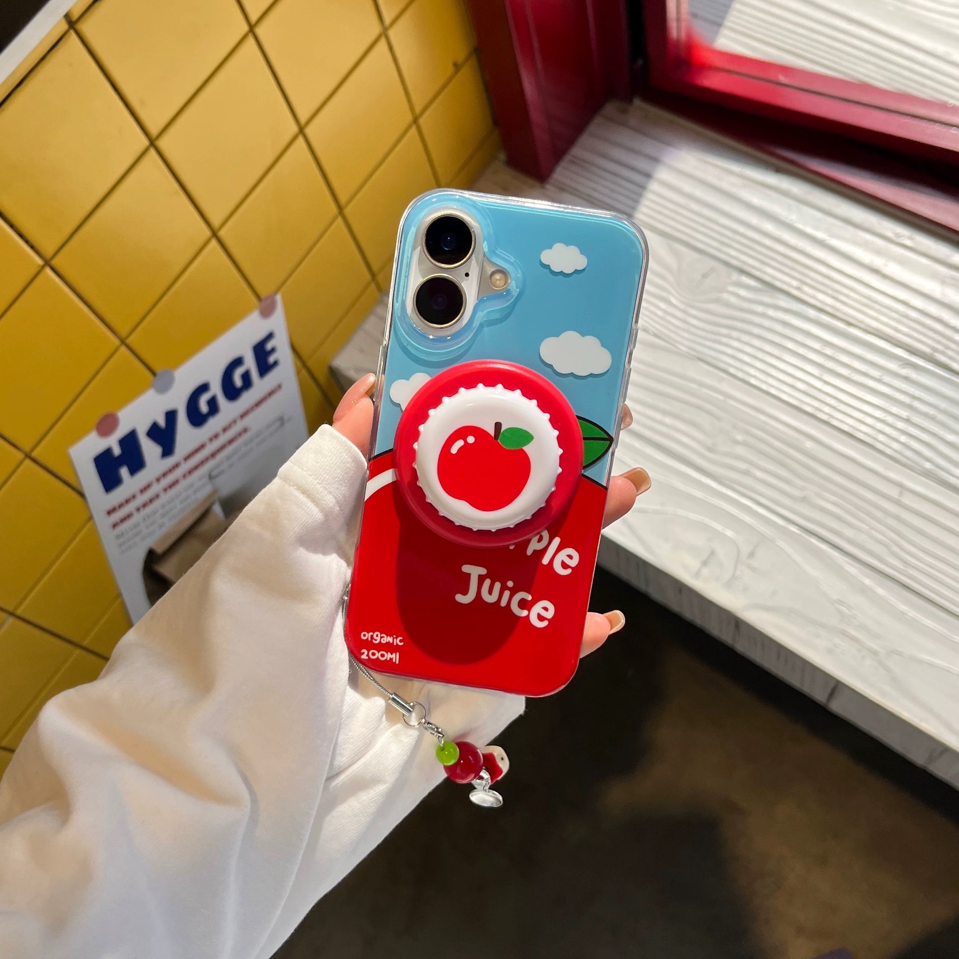 Phone case with apple juice design held by a person in a kitchen setting Fun fruitcore MagSafe case for iPhone 14 with apple print.