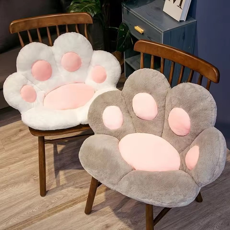 Two paw-shaped chair cushions on wooden chairs in a room setting.