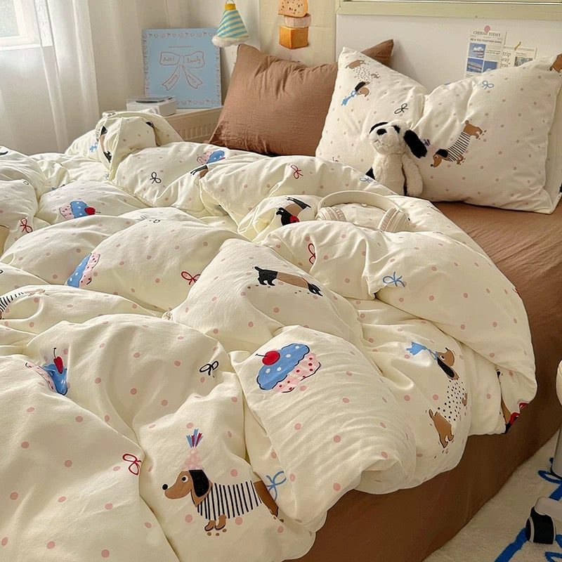 White quilt with cartoon designs on a bed in a room with a desk and window.