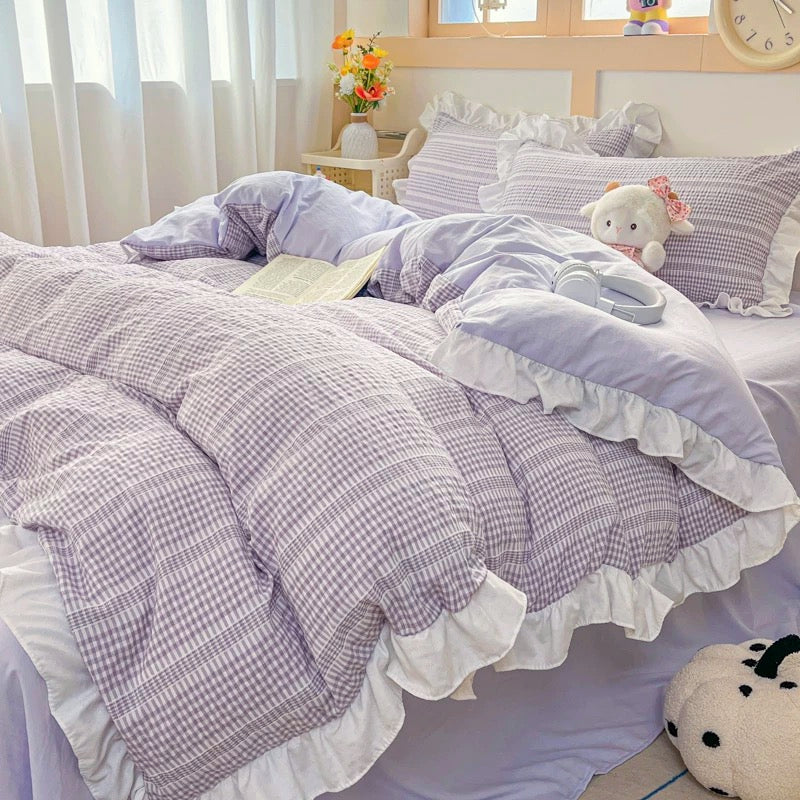 Bed with purple checkered comforter and pillows in a bright room.