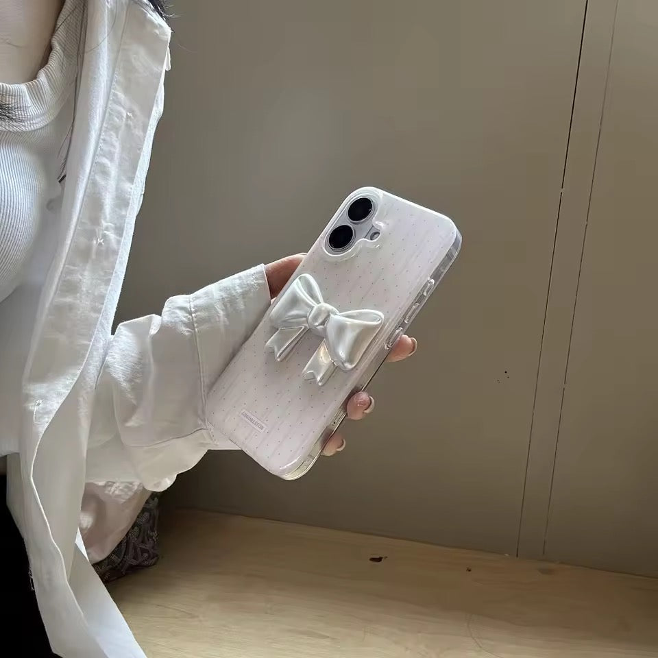 Person holding a phone with a bow design case against a neutral background