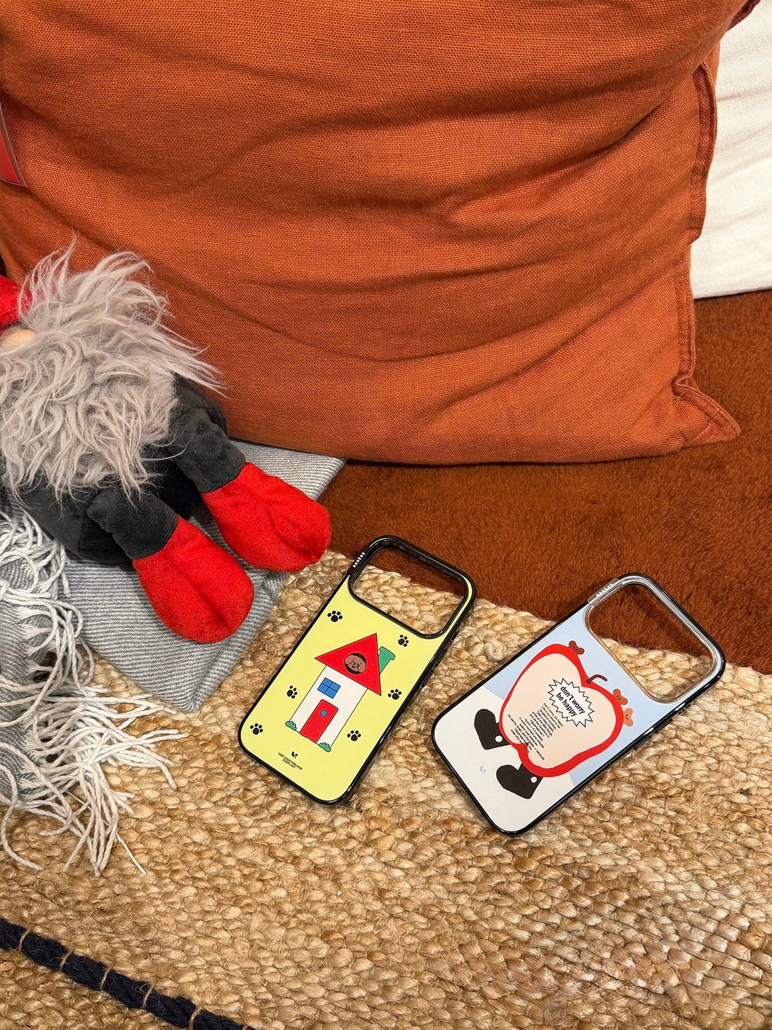 A blue cartoon phone case shows a red apple character and tiny bears as a person takes a mirror selfie.