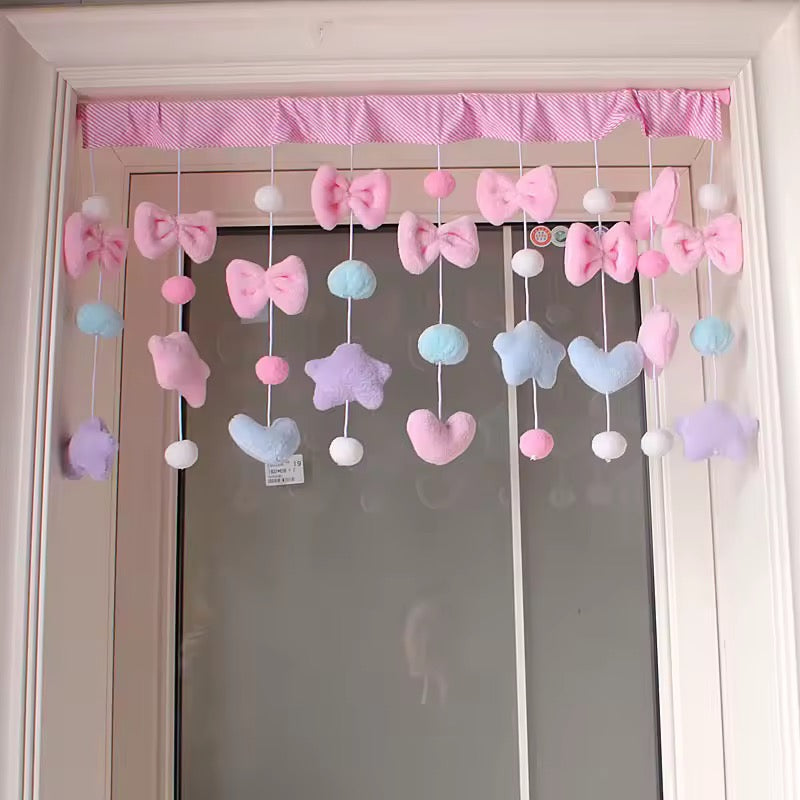 Decorative mobile with colorful bows and hearts hanging above a door.
