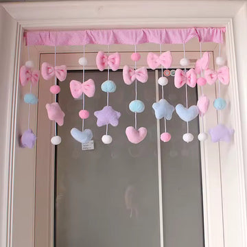 Decorative mobile with colorful bows and hearts hanging above a door.