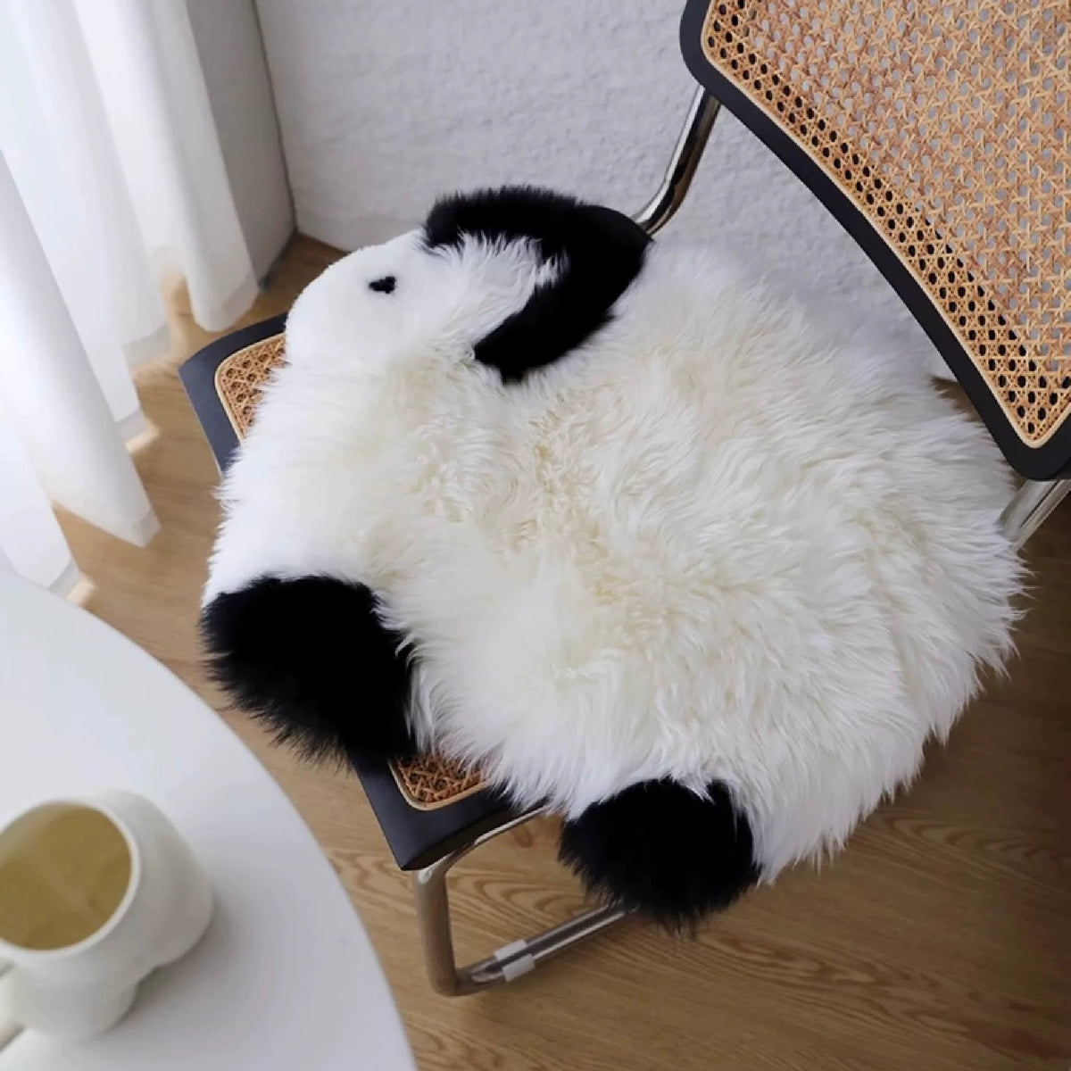 A white and black Kawaii rug drapes over a chair, with the dog face resting near the back of the seat.