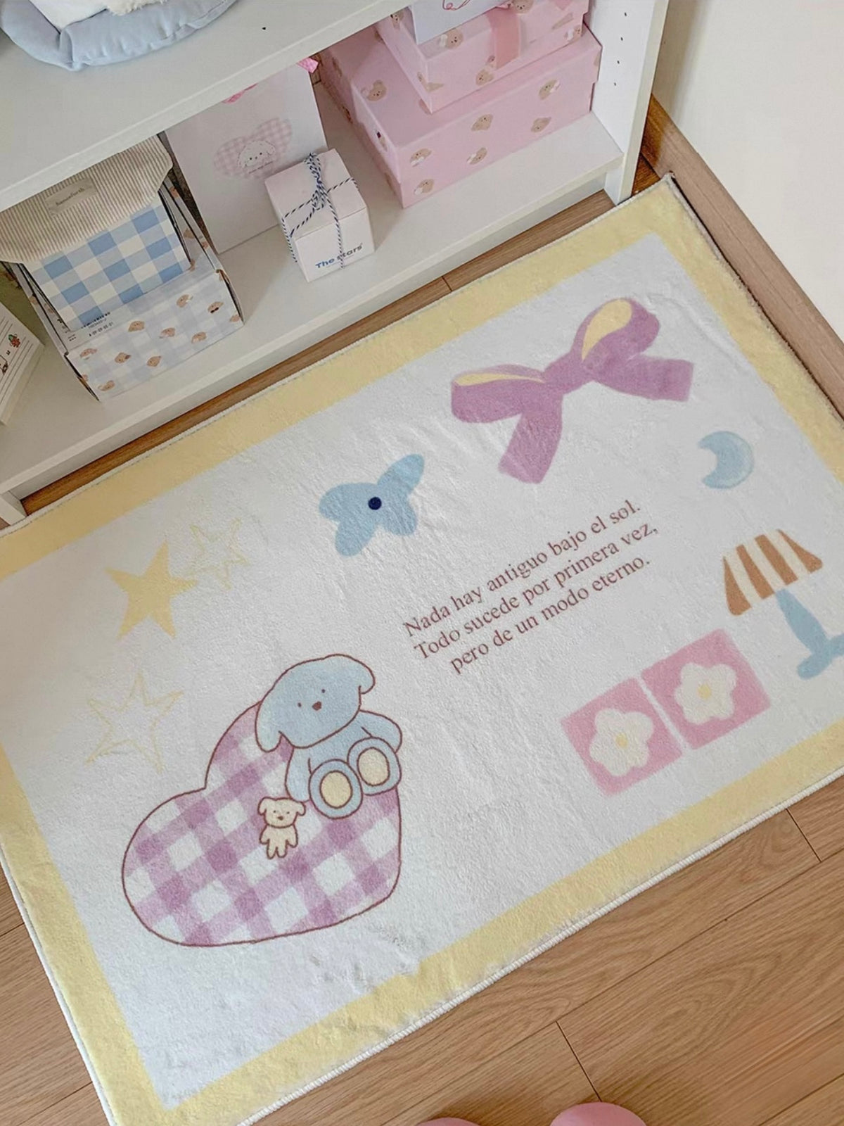 A Kawaii rug in the yellow design shows a pink bow, a blue elephant and a checked heart from an angled view.