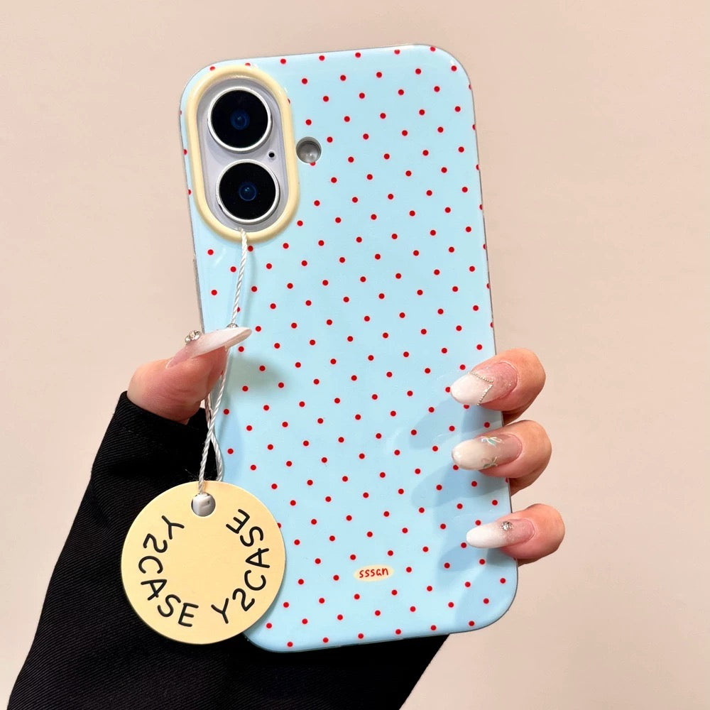Phone case with red polka dots held by a hand against a beige background