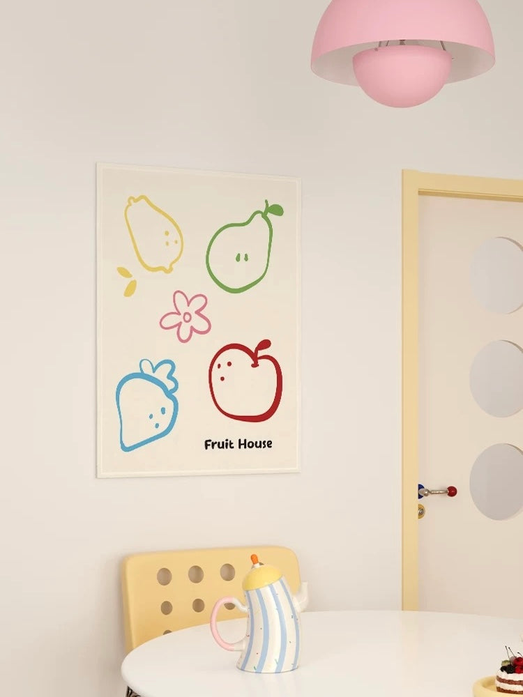 A cream kitchen tapestry with fruit outlines and Fruit House lettering hangs above a table beside a pale door.