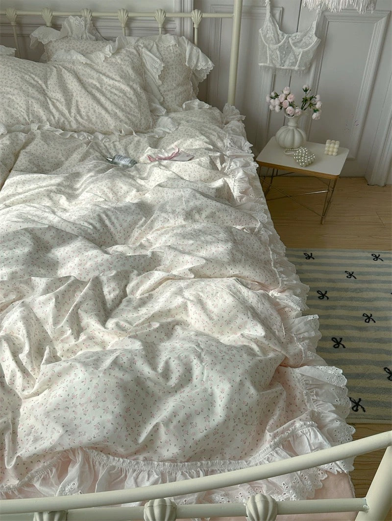 White ruffled bedding on a bed in a bedroom with a nightstand and decor.