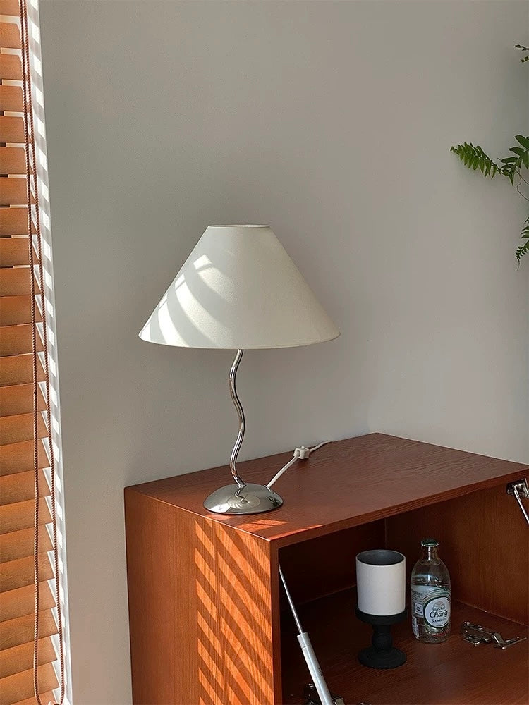Table lamp on a wooden surface with blinds in the background