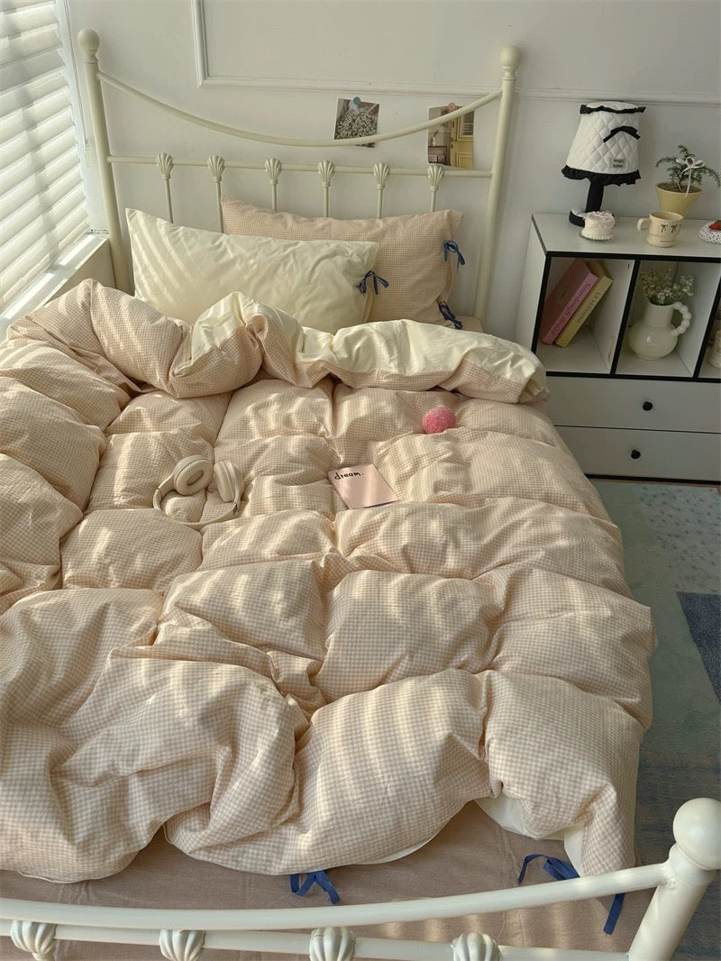 Neatly made bed with beige bedding in a bright bedroom.