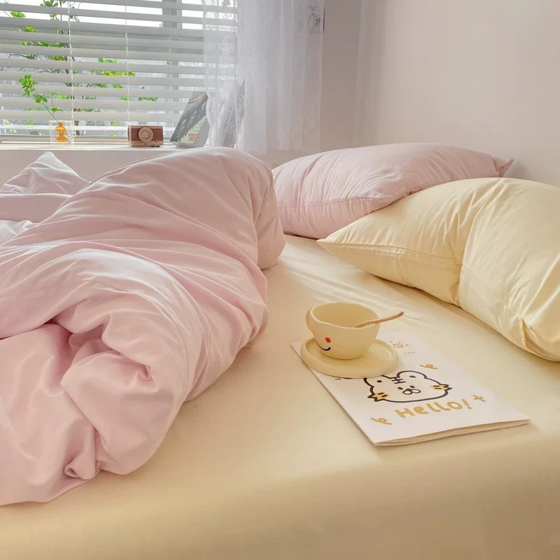 Minimalist Korean pastel bedding set featuring pink duvet cover and cream sheets on a dorm bed.