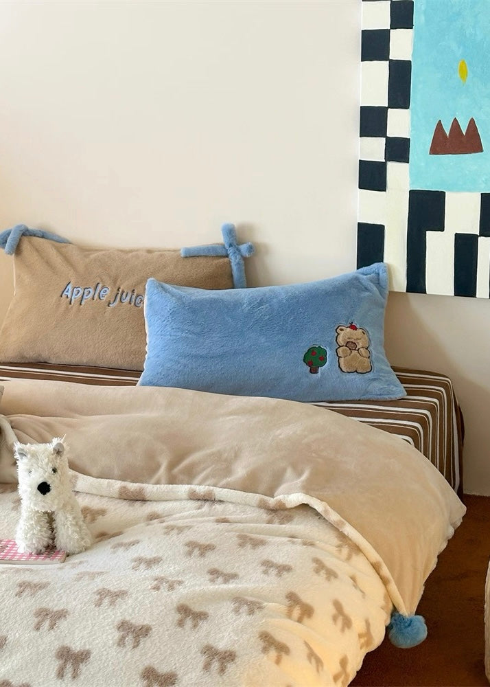 Children's bedroom with beige bedding, blue pillow, and decorative wall art.