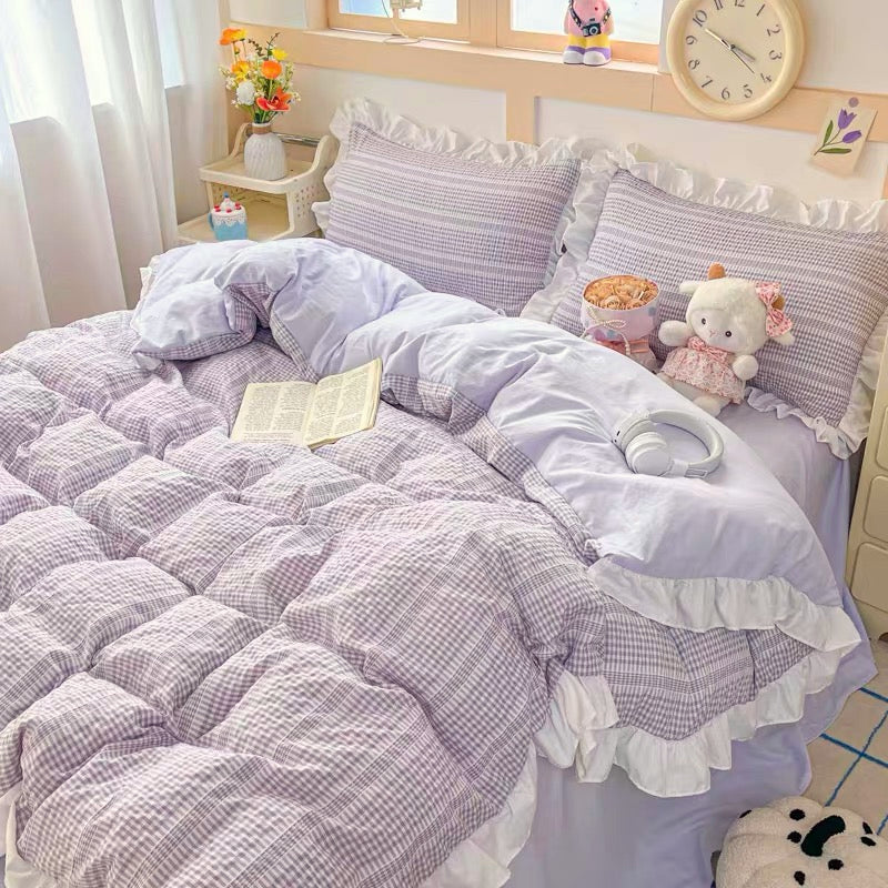Bed with checkered comforter, pillows, and a teddy bear in a room setting.