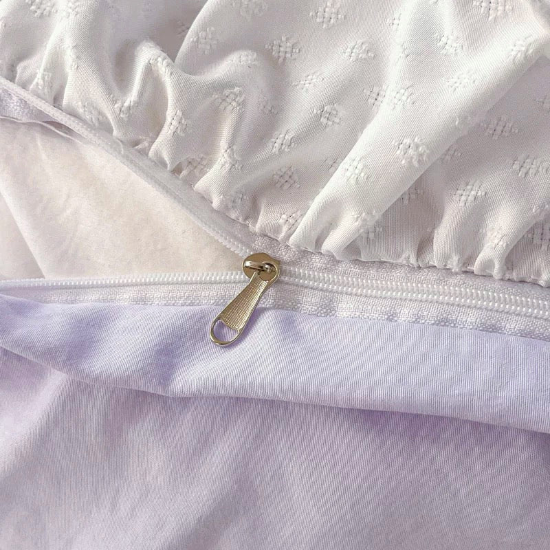 Close-up of a white mattress cover with a zipper, showing texture and fabric details.