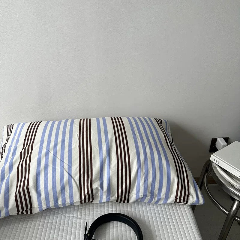Striped pillowcase on a bed with a nightstand in the background