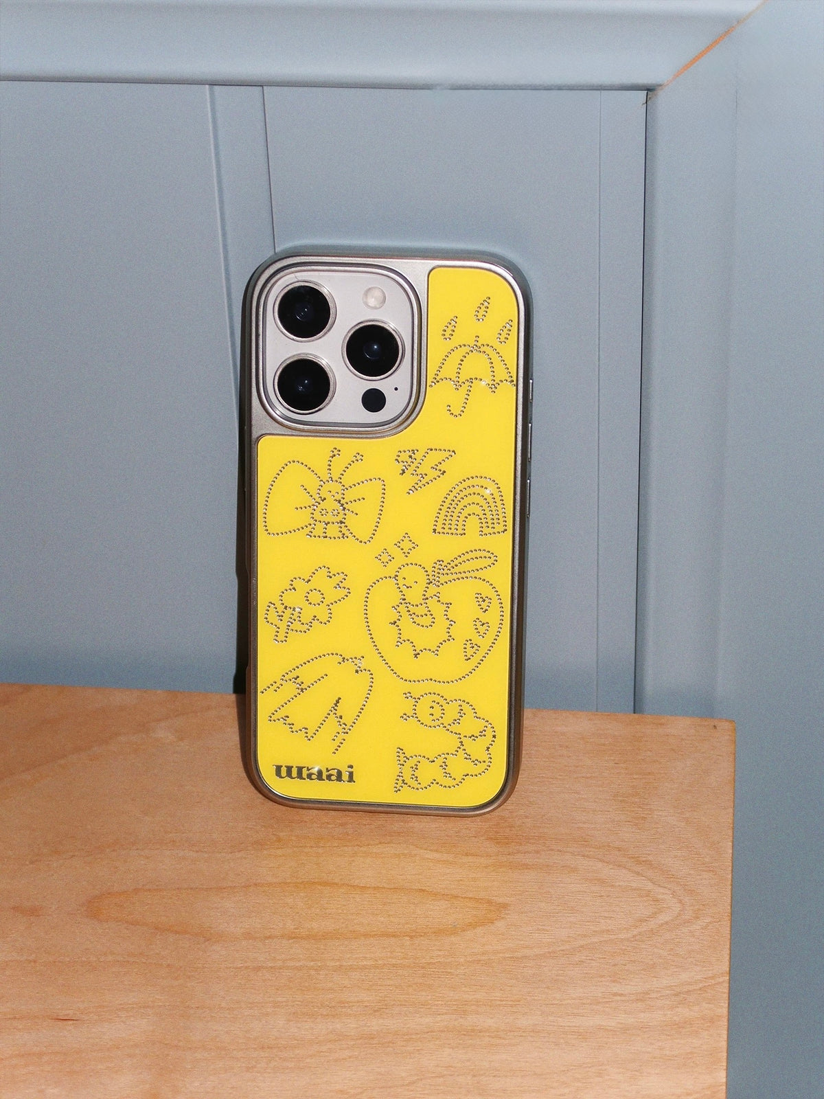 A lemon yellow phone case shown straight on, displaying the dotted silver artwork and colored back.