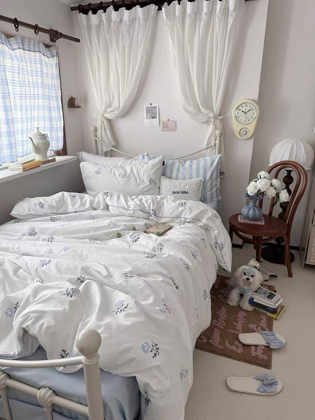 Bedroom with white bedding and decorative pillows, featuring a clock on the wall.