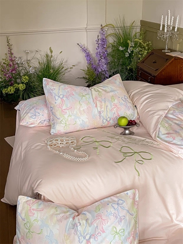 Bed with floral-patterned bedding and pillows, surrounded by decorative plants and a small table.