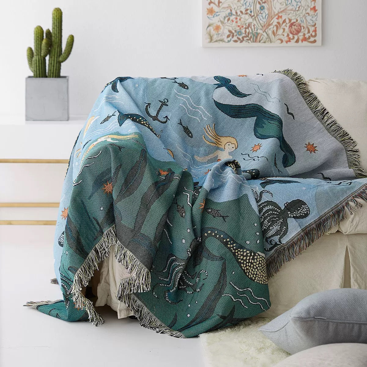 Mermaid-themed blanket draped over a couch in a living room setting.