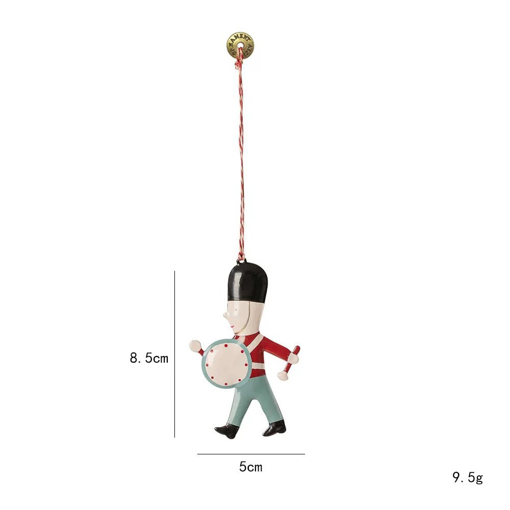 A metal Christmas ornament shows a soldier with a black hat, red jacket and a round white drum.