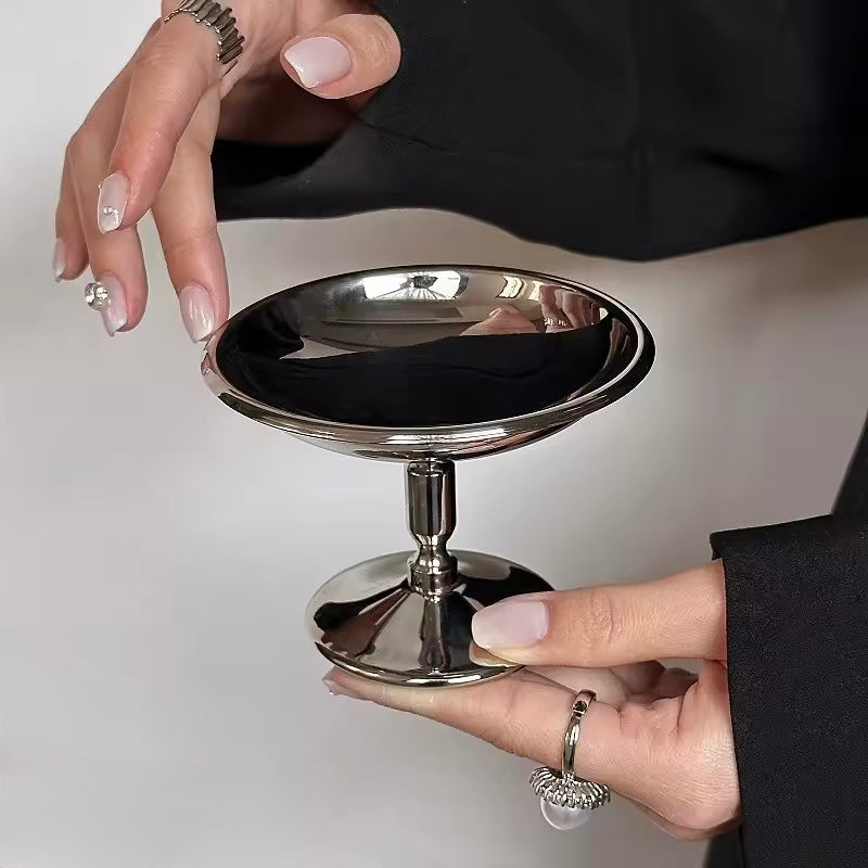 Person holding a small metallic stand with a reflective surface