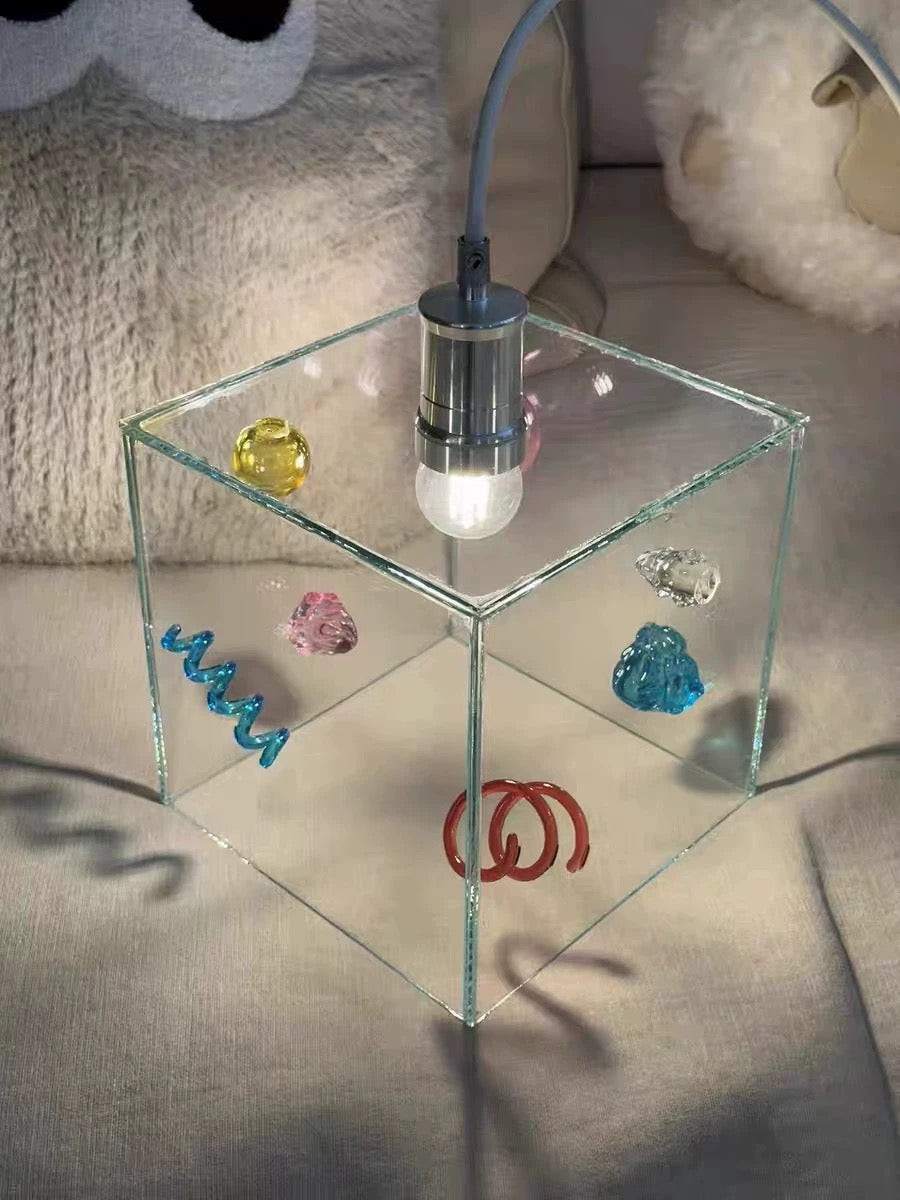 Glass side table with decorative stones and a lamp on a soft surface