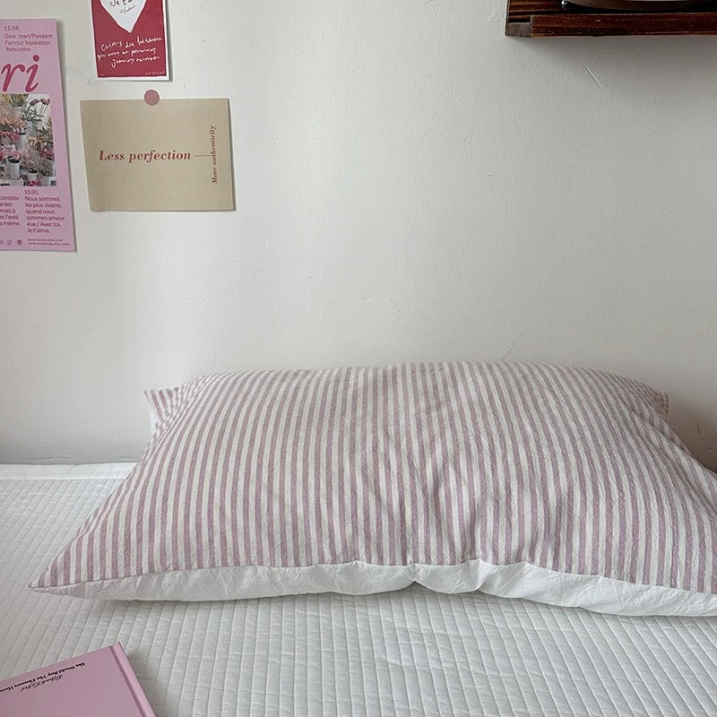 Striped pillow on a bed with motivational posters on the wall