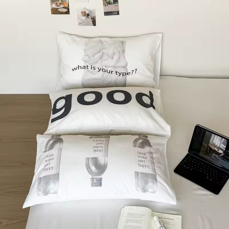 Three white printed pillowcases stacked on a bed, featuring black text and bottle illustrations. The top pillowcase reads 'what is your type??', the middle reads 'good', and the bottom reads 'what is your type again?'.