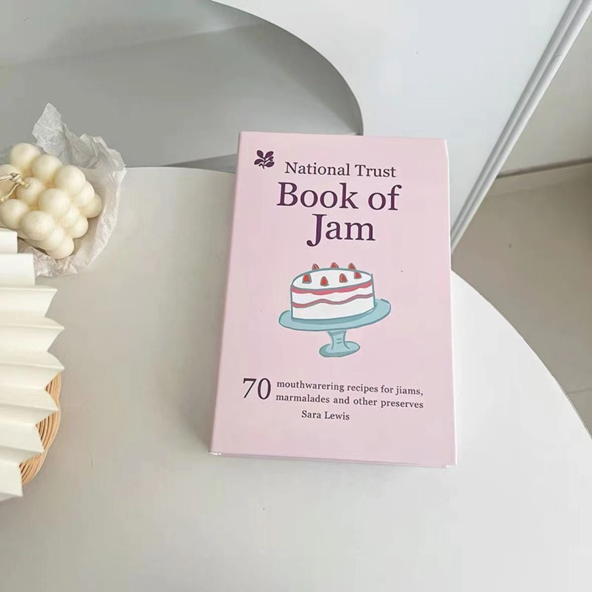 Book titled 'National Trust Book of Jam' on a white surface with decorative elements.