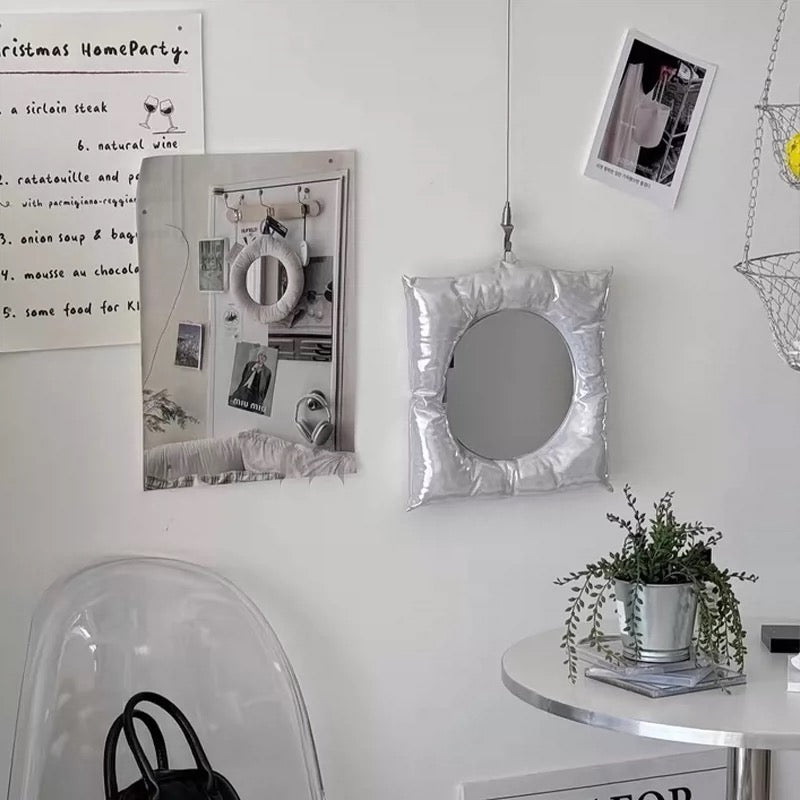 Silver-framed mirror on a white wall with decorative elements