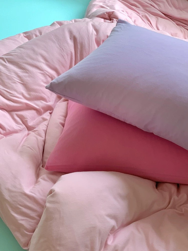 Pink bedding set with two pillows on a light blue background