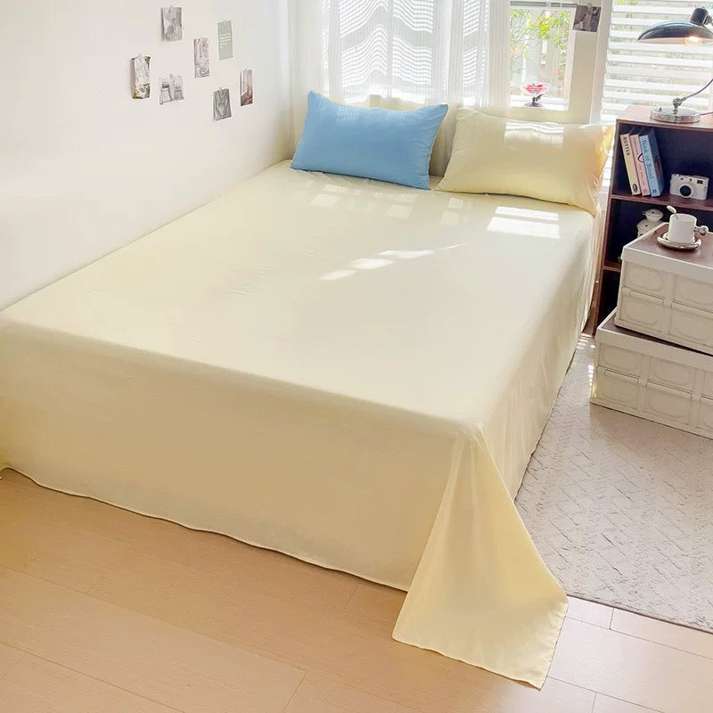 Beige bedspread on a bed in a room with a window and shelves.