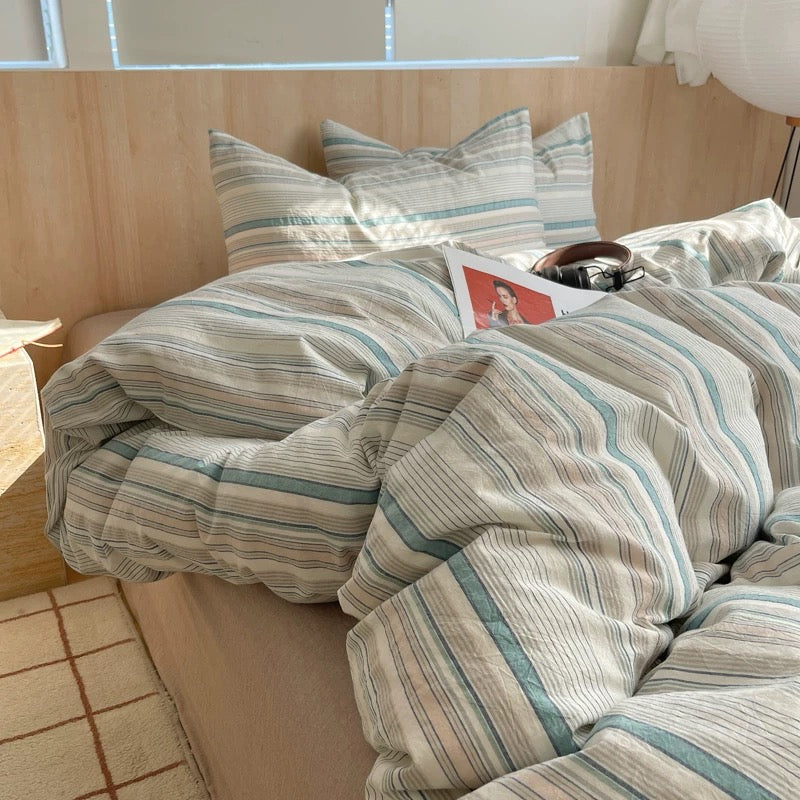 Thin blue stripe duvet cover cotton bedding photographed in bright modern Scandinavian style apartment bedroom interior